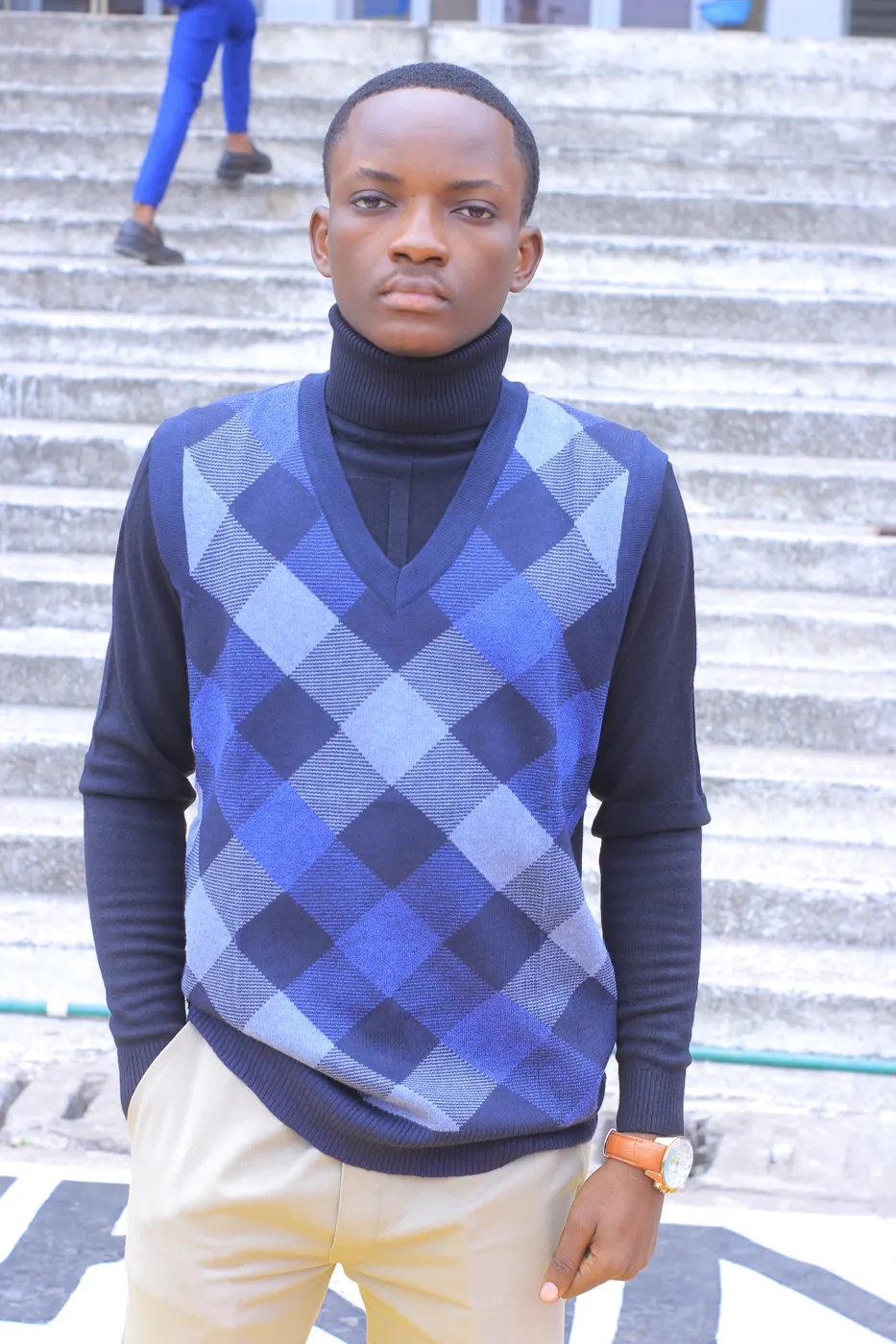 Portrait de Béni Mbeko en pull à motifs, en extérieur